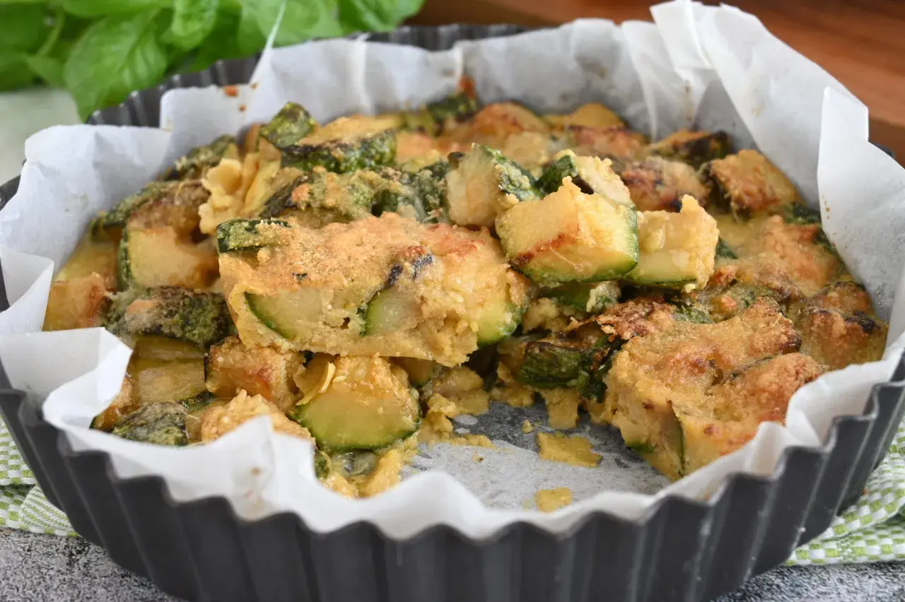 Deliziosi zucchine al forno, dorati e fragranti, in una tortiera foderata di carta forno.