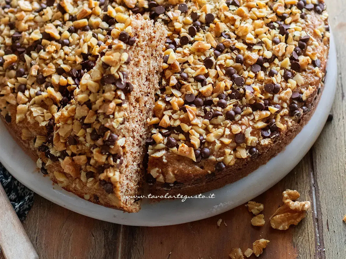 Torta di noci della nonna, soffice e golosa, ricoperta di noci tritate e gocce di cioccolato. Un classico intramontabile.