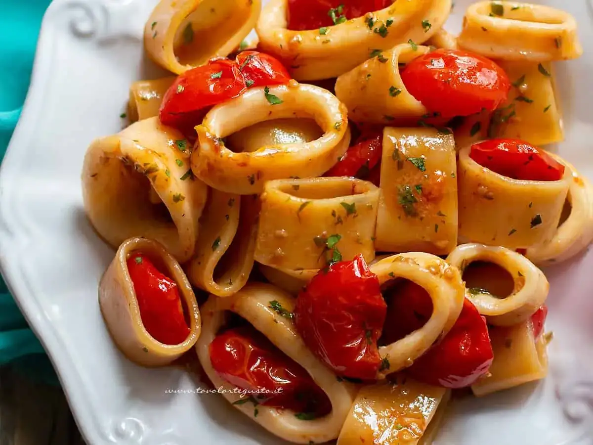 Un piatto invitante di pasta con calamari e pomodorini, condito con erbe aromatiche.