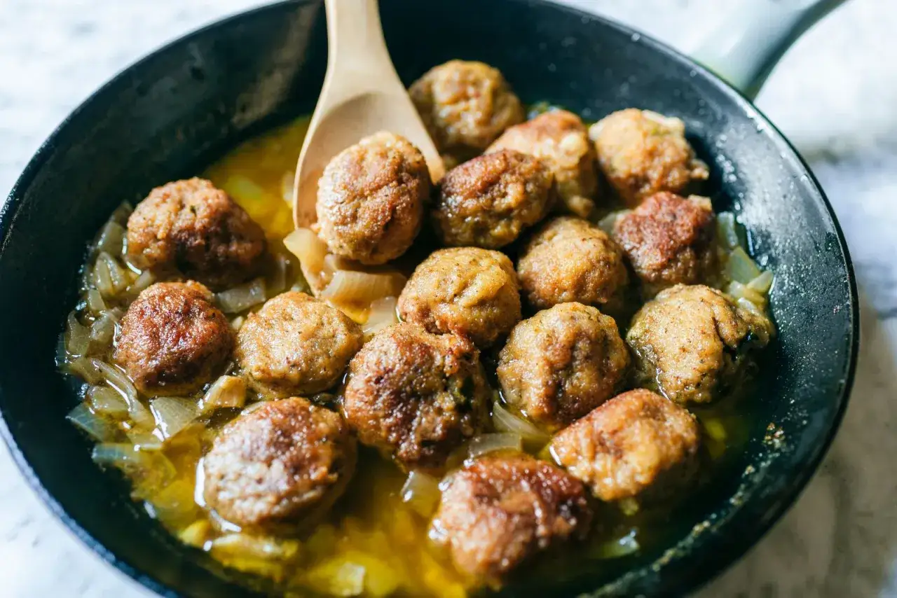 Polpette in bianco cotte in padella con cipolle, pronte per essere gustate.