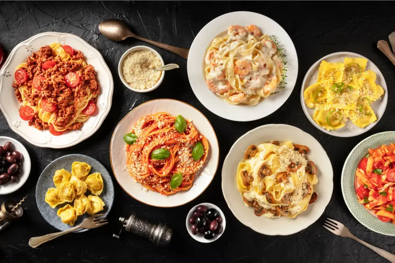 Varietà di condimenti per pasta: spaghetti al ragù, fettuccine ai gamberi, ravioli, tortellini, pasta ai funghi e penne al pomodoro.