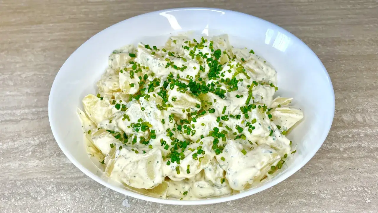 Una cremosa insalata di patate, condita con erbe aromatiche e guarnita con erba cipollina fresca. Perfetta per un picnic o un pranzo leggero.