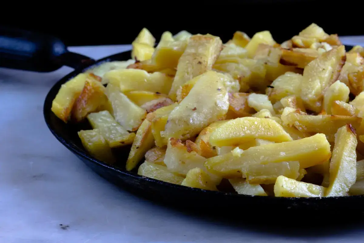 Patate in tecia, dorate e croccanti, servite in una padella di ghisa. Un contorno rustico e saporito.