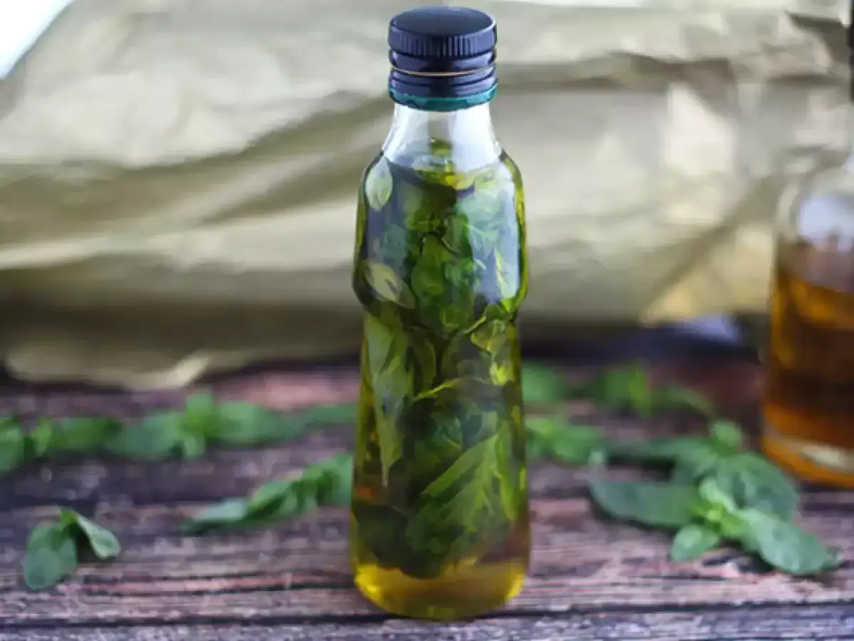 Olio al basilico fatto in casa da Benedetta, profumato e verde brillante, in una bottiglia di vetro.
