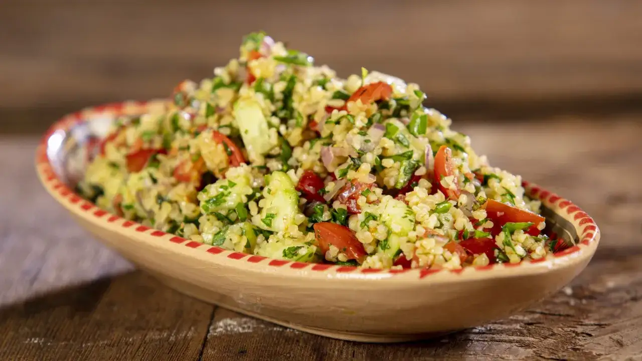 Un invitante tabul&egrave; di verdure, ricco di pomodori, cetrioli e prezzemolo fresco, servito in una ciotola decorata.