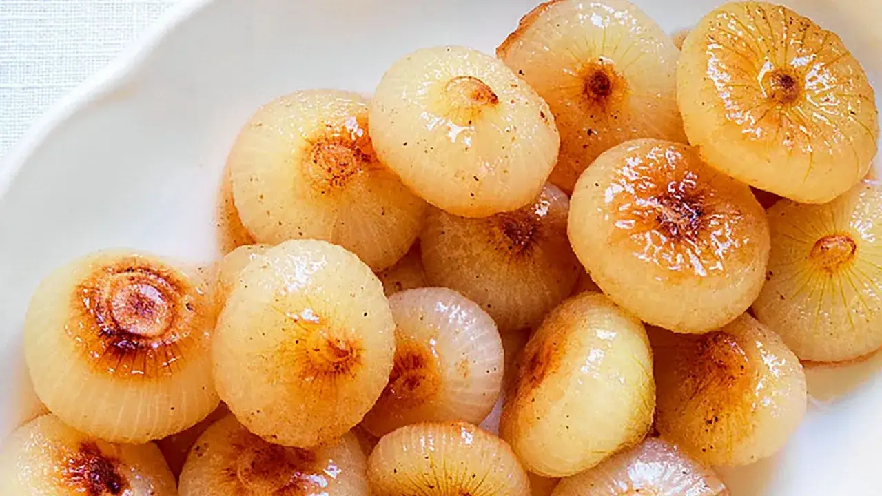 Cipolline in agrodolce, caramellate e lucide, servite in una ciotola bianca.