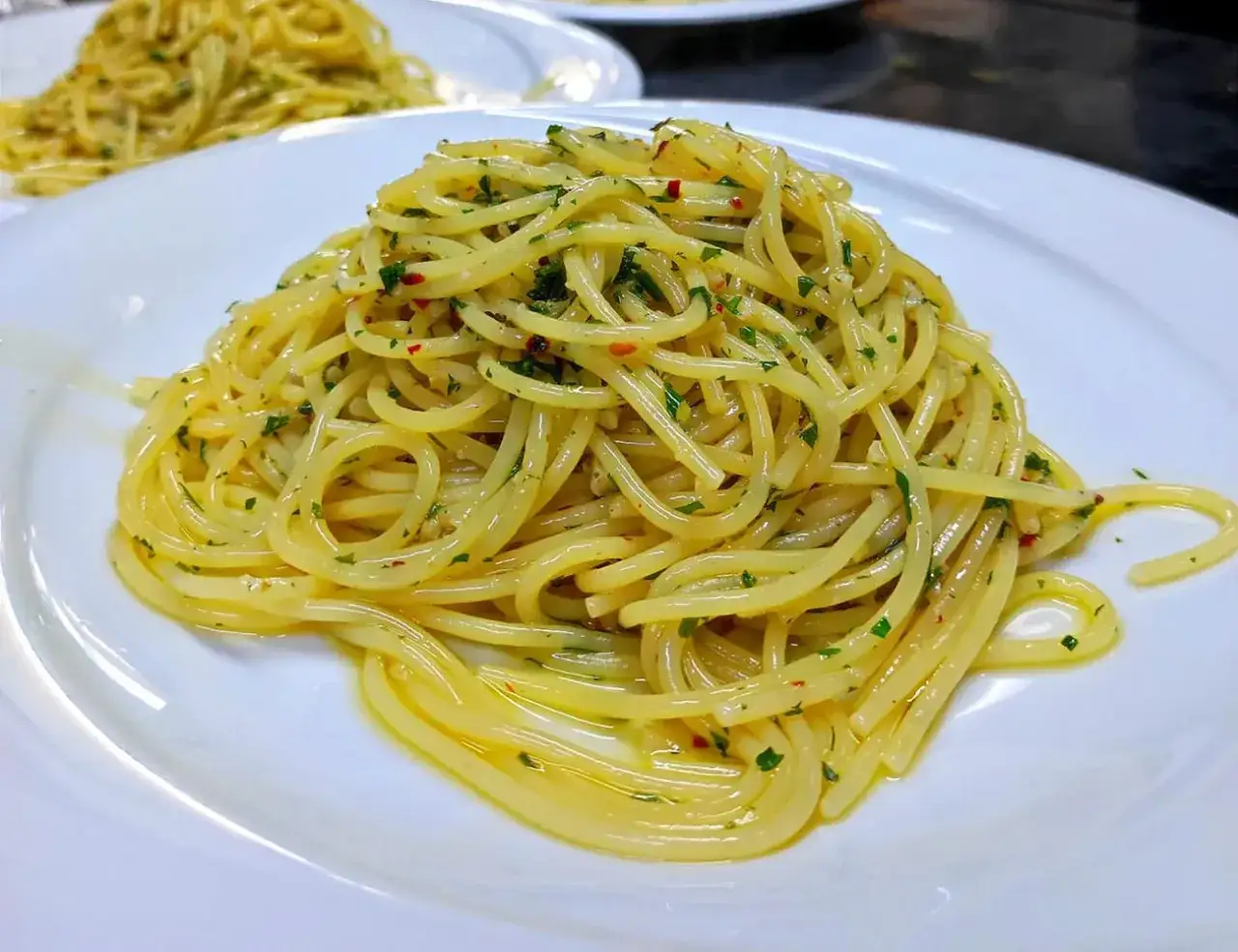 Spaghetti aglio olio e peperoncino cremosi, un classico invitante, conditi con prezzemolo fresco e un filo d'olio dorato.