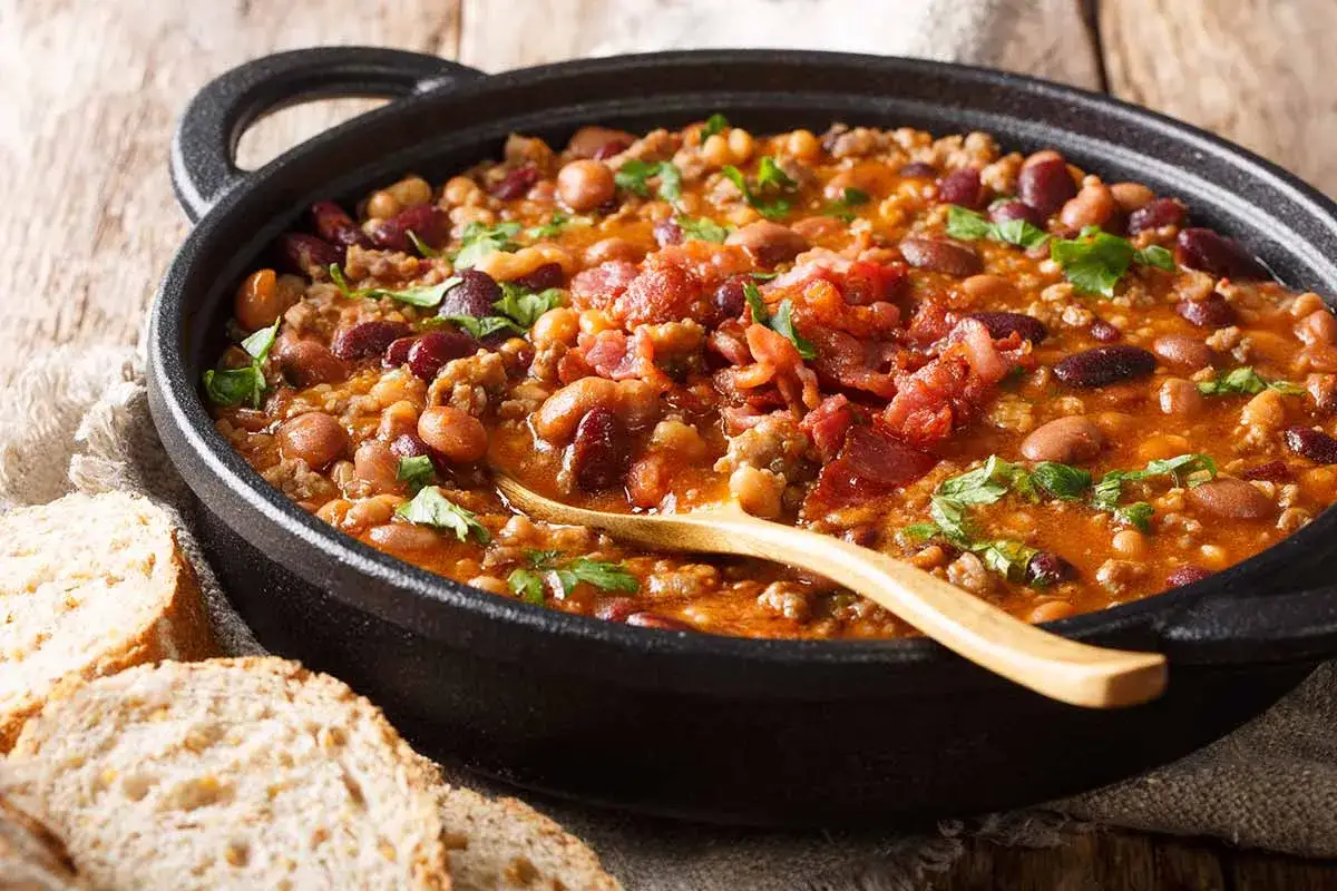 Un saporito piatto di fagioli alla Bud Spencer, ricco di carne e pancetta croccante, pronto per essere gustato con pane rustico.