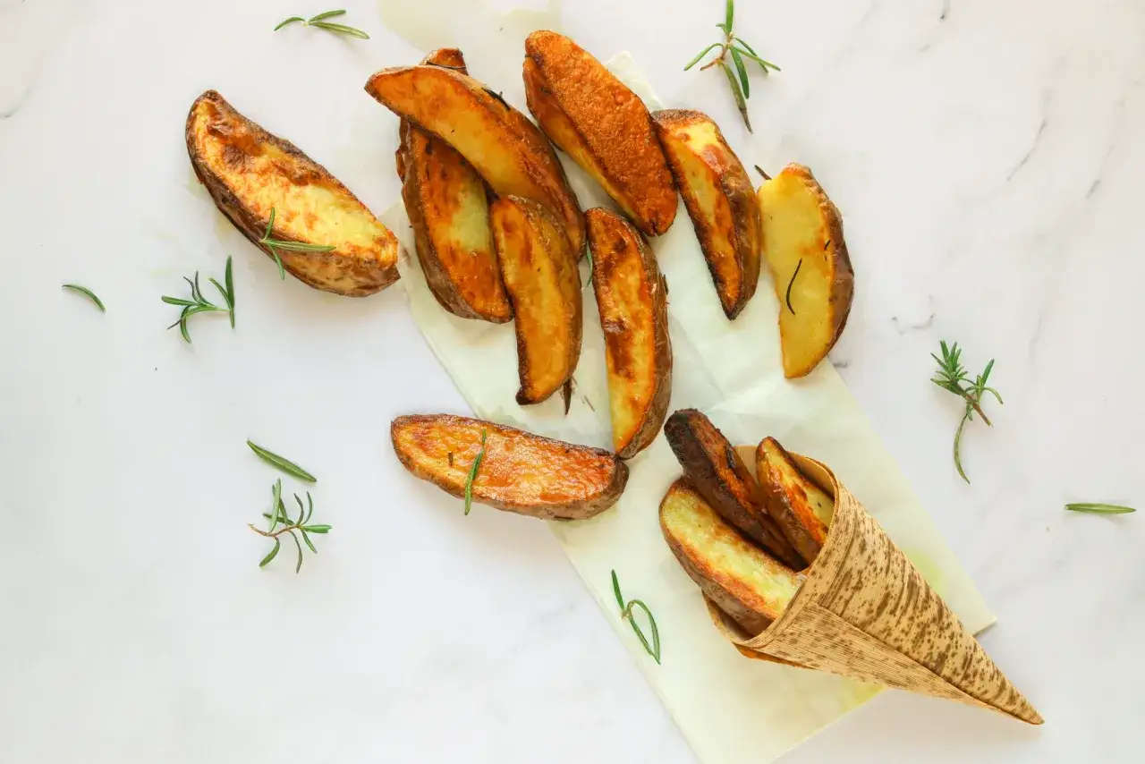 Patate al forno veloci, dorate e croccanti, guarnite con rosmarino fresco. Perfette per uno spuntino rapido e gustoso.