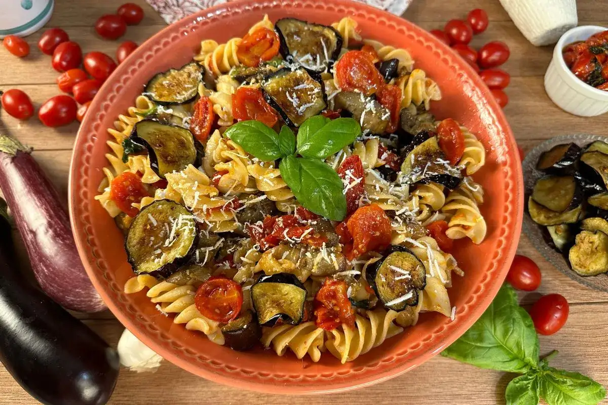 Pasta fredda con melanzane grigliate, pomodorini e basilico fresco, un piatto estivo colorato e saporito.