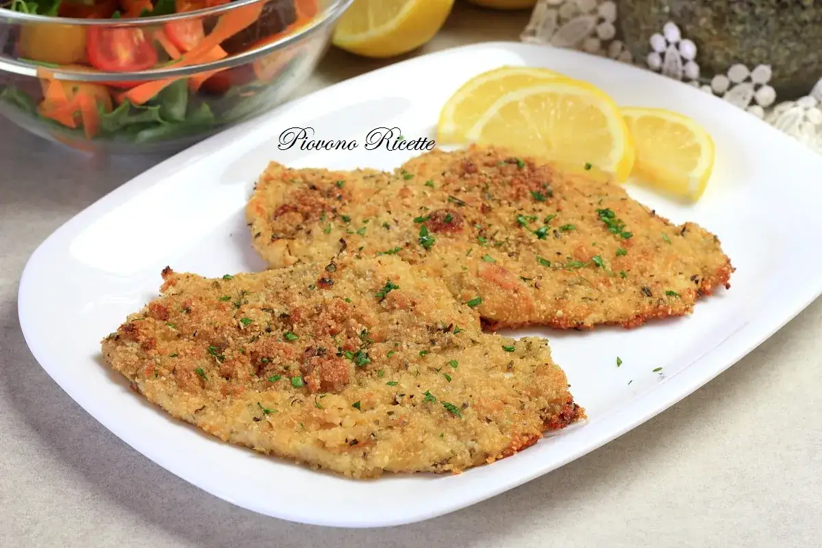 Due cotolette al forno dorate e croccanti, guarnite con prezzemolo fresco e servite con spicchi di limone e un'insalata mista.