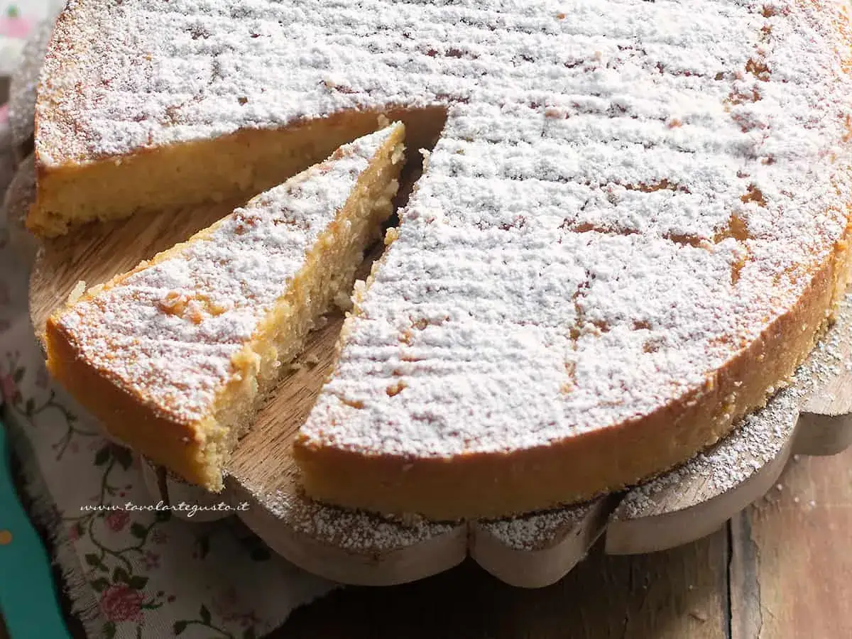 Una fetta di torta di riso, soffice e cosparsa di zucchero a velo, attende di essere gustata.