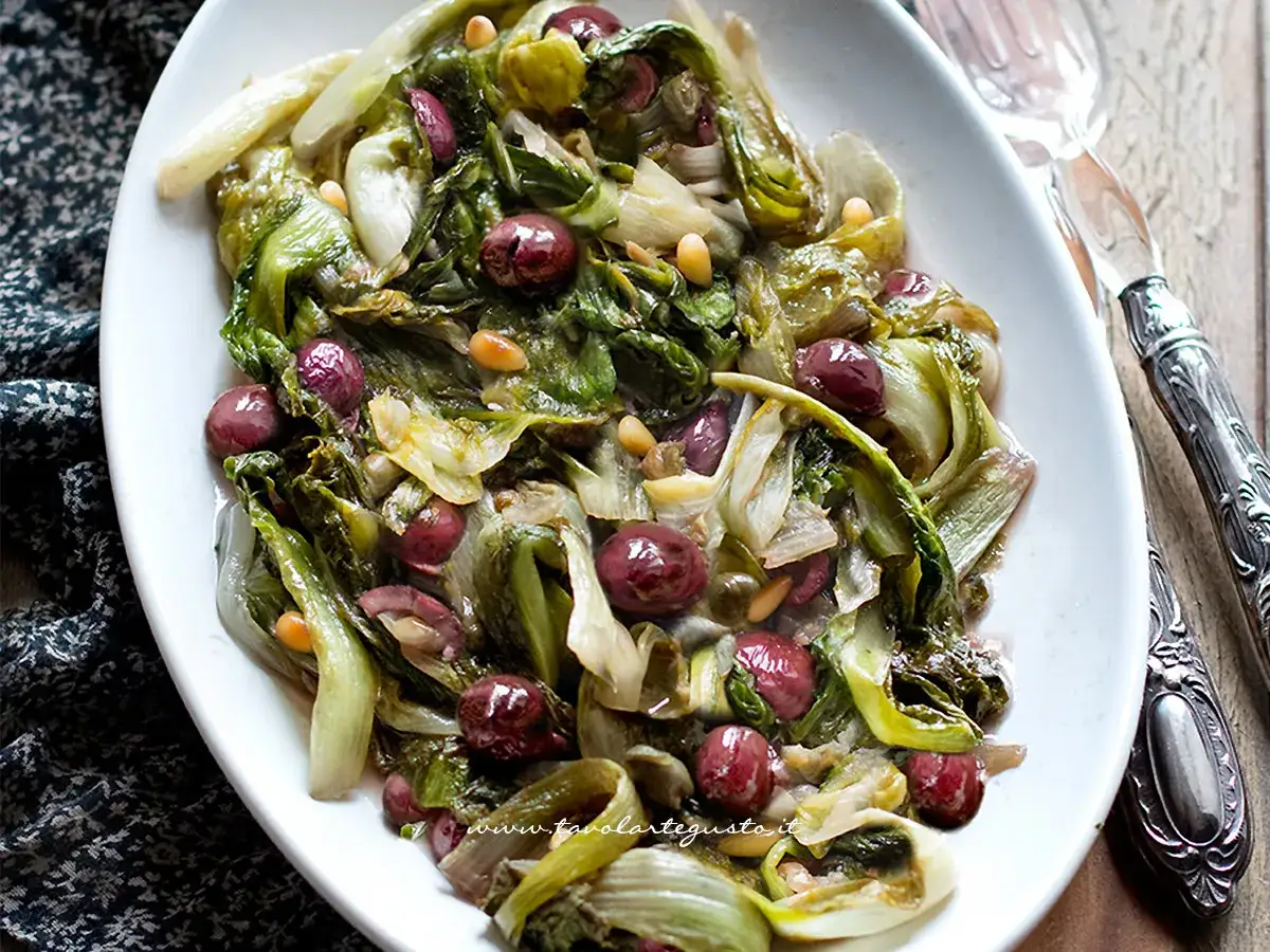Scarola in padella con olive e pinoli, un contorno saporito e colorato, pronto per essere gustato.