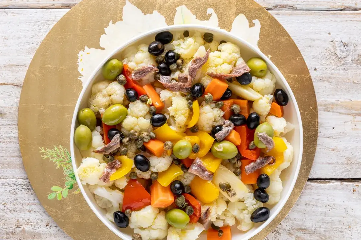 Insalata di rinforzo colorata con cavolfiore, olive, peperoni, carote e acciughe.