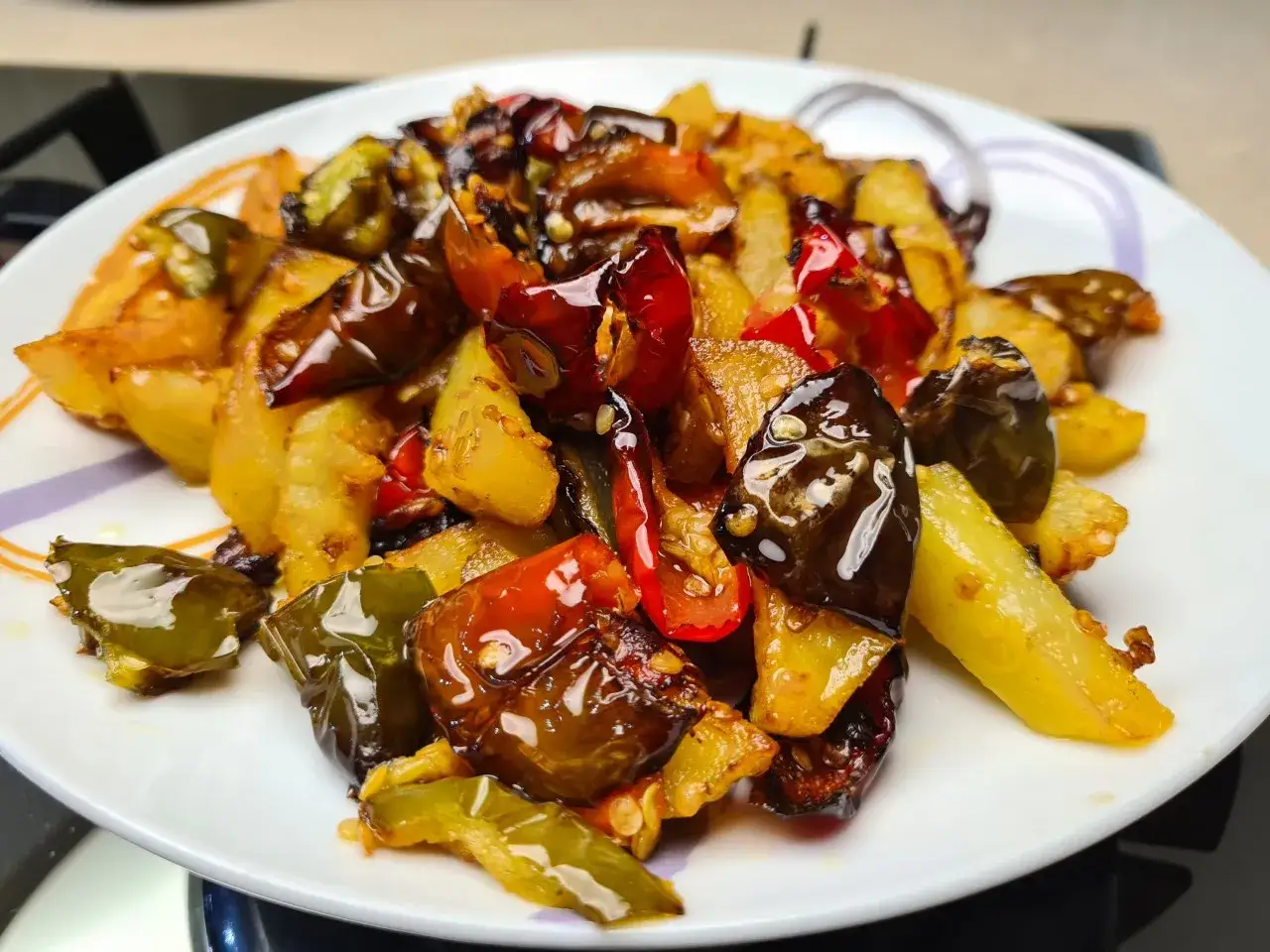 Un piatto invitante di pipi e patate saltate, con peperoncini rossi e verdi lucidi e patate dorate.