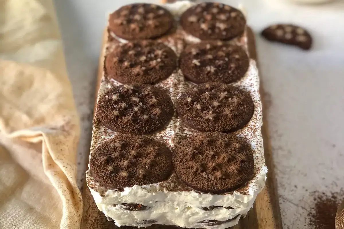 Deliziosa torta pan di stelle fredda, stratificata con crema e biscotti al cacao, spolverata di cacao.