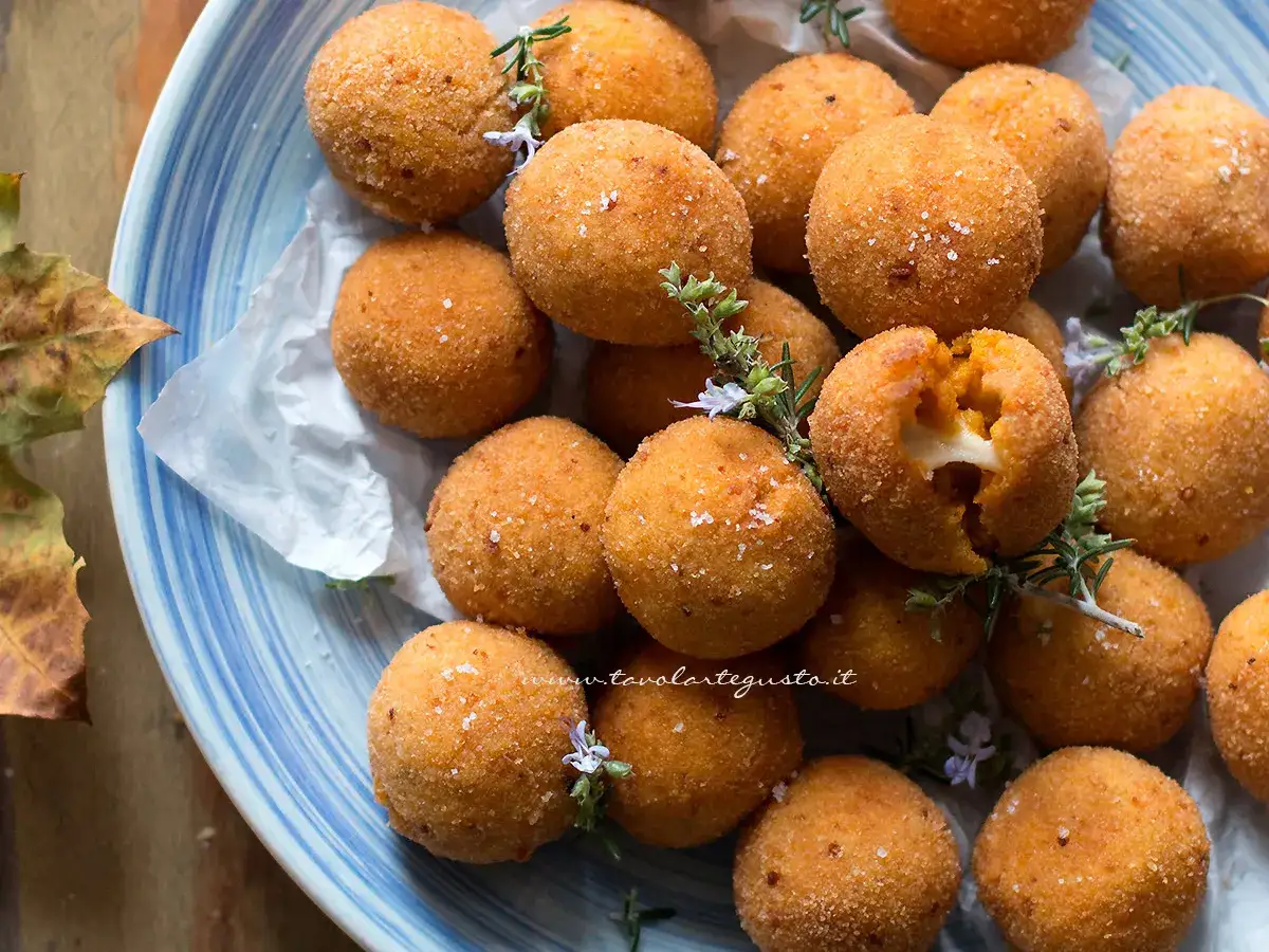 Deliziose polpette di zucca dorate e croccanti, alcune con un cuore filante di formaggio. Guarnite con erbe aromatiche e sale grosso.