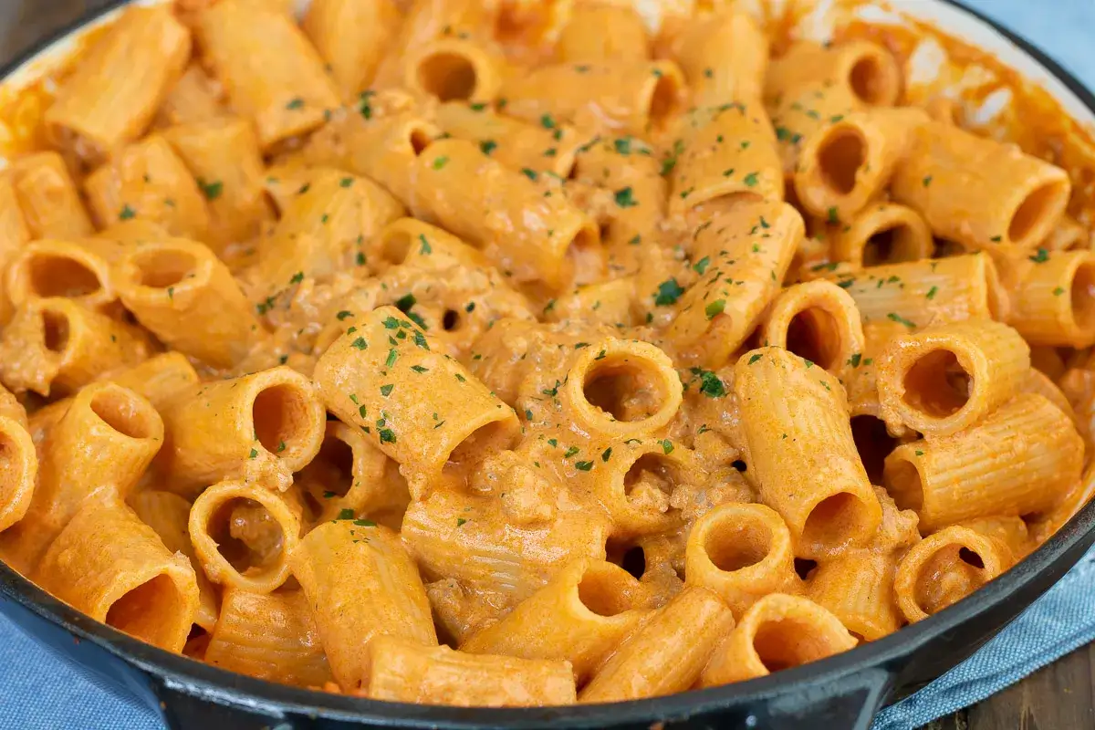 Un primo piatto succulento: pasta alla carcerata cremosa e ricca, condita con un sugo rosato e prezzemolo tritato.