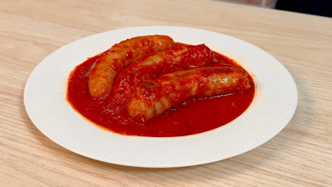 Salsicce in sugo rosso, un classico sugo con salsiccia ricetta della nonna, servite su un piatto bianco.
