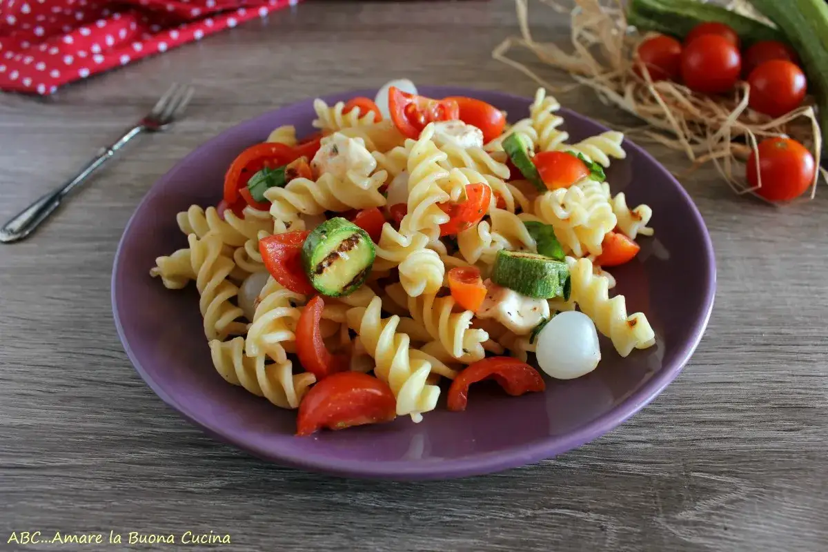 Pasta fredda con zucchine grigliate, pomodorini e mozzarelline su un piatto viola. Un piatto estivo perfetto!